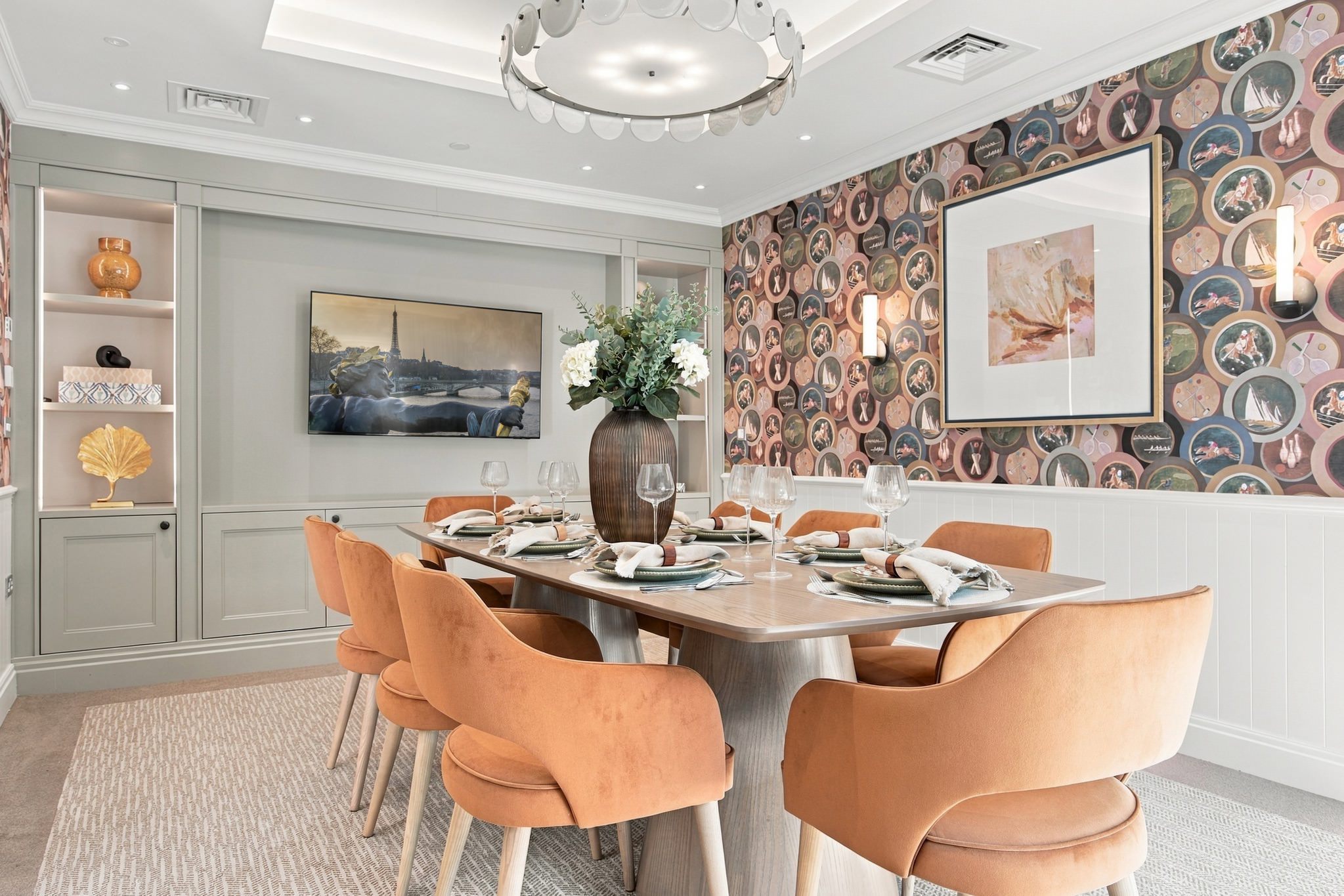 Private dining room with a long table, terracotta velvet chairs and bold sporting-themed wallpaper.